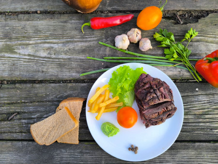 juicy steak on a white plate surrounded by vegetables.の写真素材