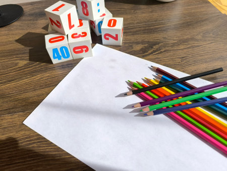 Cubes with numbers, pencils and a white sheet of paper on the table. High-quality photosの写真素材