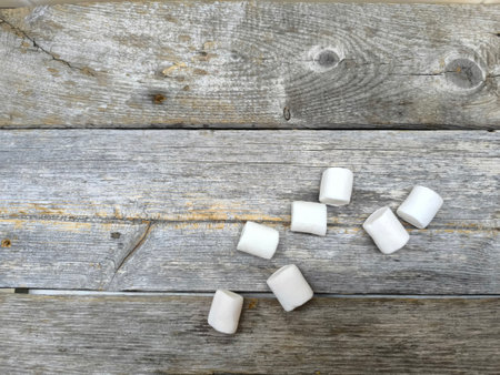 Scattered pieces of marshmallow lie on a wooden table.の写真素材