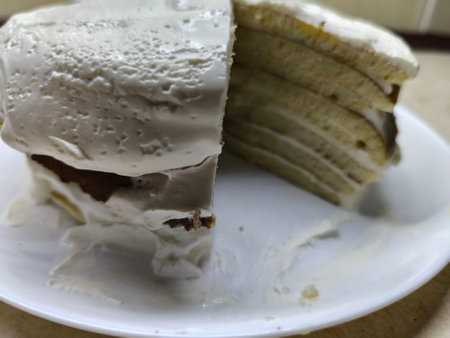 layered cake made of pancakes and sour cream lies on a white plate
