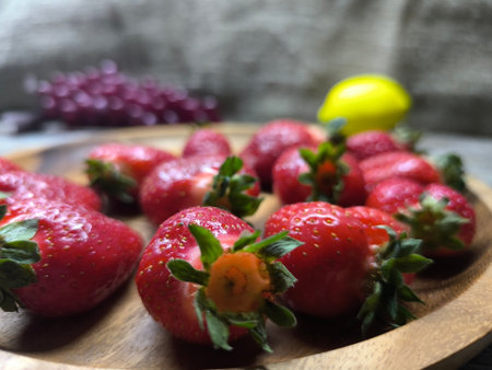 Ripe sweet strawberries in a wooden plate on a woodenの写真素材
