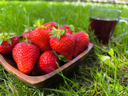ripe fresh strawberries in a plate close-up on green grass backgroundの写真素材