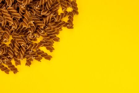 Fusilli pasta spirals on yellow backgroundの写真素材