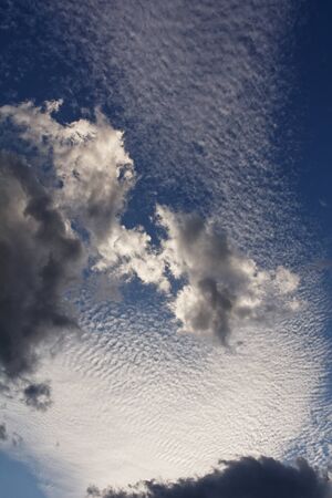 Blue sky with clouds in the rays of the setting sun, dramatic effect