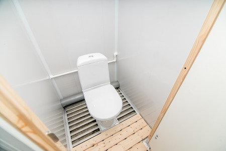 The photo of the bright public toilet room with standing in it a white toilet bowlの写真素材