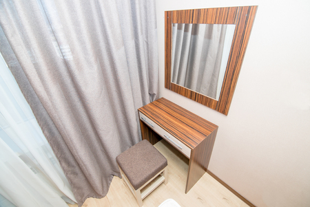 The photo of the light room of a table with a mirror for cosmeticsの写真素材