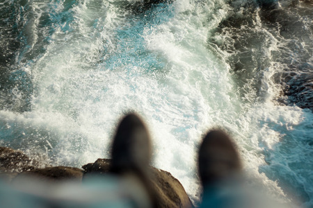 The person sits at break over the sea where big waves breakの写真素材