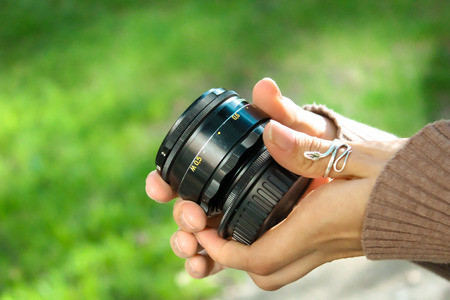 The young girl holds an old, vintage, black lens in handの写真素材