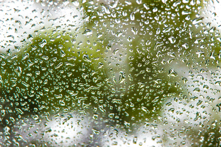The drops which are flowing down on glass after a heavy rainの写真素材