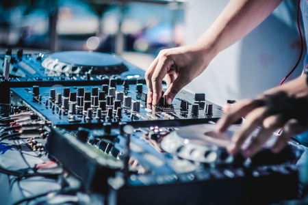 The photo of the DJ mixer and players of disks with handsの写真素材