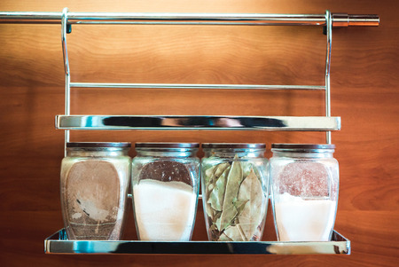 The photo of spices for cooking, in glass jars hanging on a wallの写真素材