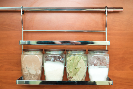 The photo of spices for cooking, in glass jars hanging on a wallの写真素材