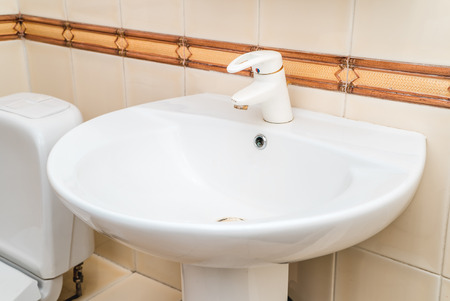 The photo of a white clean sink with the crane in the bathroomの写真素材