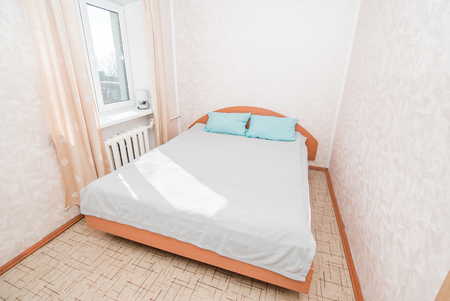 The photo of the bright bedroom with a bed at a windowの写真素材