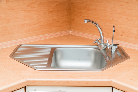 The photo of a white clean sink with the crane in the kitchenの写真素材