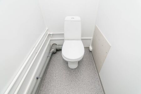 The photo of the bright public toilet room with standing in it a white toilet bowlの写真素材