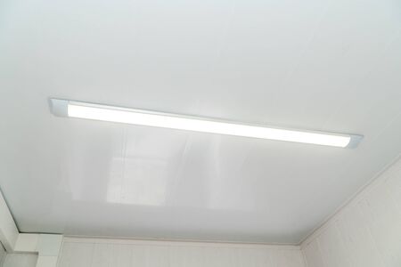 The photo of a bright chandelier on a white metal ceilingの写真素材