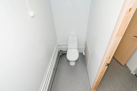 The photo of the bright public toilet room with standing in it a white toilet bowlの写真素材