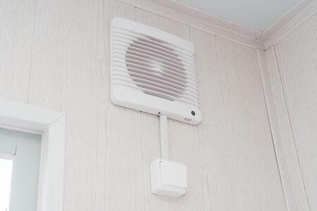 The photo of the fan on a white wall for air circulationの写真素材