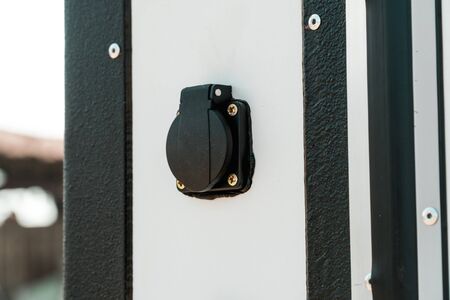 Photo of a moisture-proof black socket on a white wall