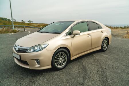 Photo of a car of gold color standing in a parking lot on the streetの写真素材