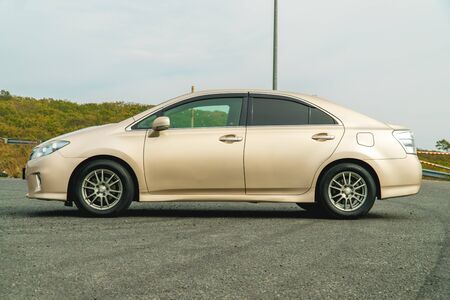 Photo of a car of gold color standing in a parking lot on the streetの写真素材