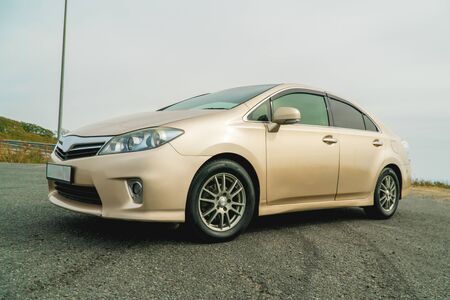 Photo of a car of gold color standing in a parking lot on the streetの写真素材