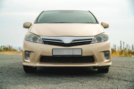 Photo of a car of gold color standing in a parking lot on the streetの写真素材