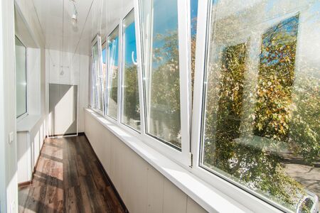 The photo of a bright balcony with wooden floor and white windowsの写真素材