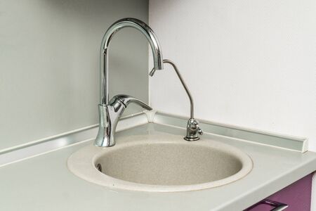 The photo of a white clean sink with the crane in the kitchenの写真素材
