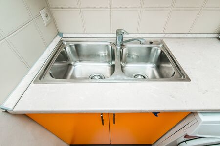 The photo of a white clean sink with the crane in the kitchenの写真素材