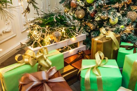 Decorated boxes with New Year gifts tied with ribbons lying under the tree.の写真素材