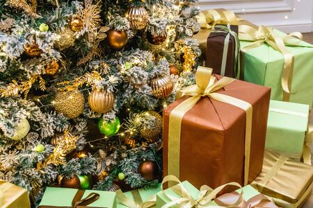 Decorated boxes with New Year gifts tied with ribbons lying under the tree.の写真素材