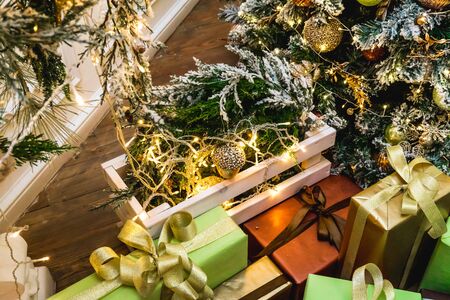 Decorated boxes with New Year gifts tied with ribbons lying under the tree.の写真素材