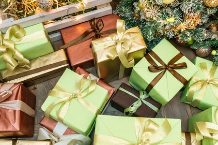 Decorated boxes with New Year gifts tied with ribbons lying under the tree.の写真素材