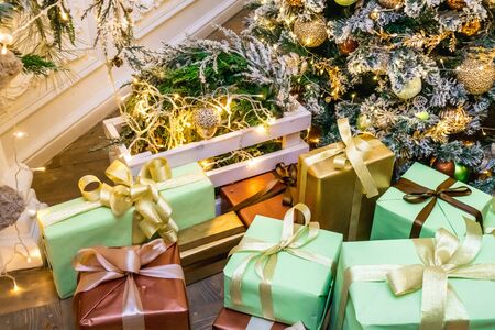 Decorated boxes with New Year gifts tied with ribbons lying under the tree.の写真素材