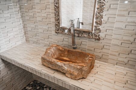 Photo of bathroom with sink made of a piece of wood and with mirror on the wallの写真素材