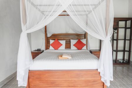 Bright photo of a room with a wooden bed under a maskite gridの写真素材