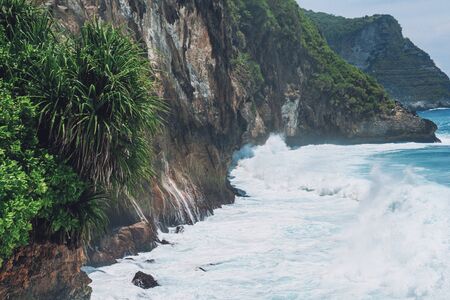Photo of large waves crashing into large rocks on Nusa Penida island in Indonesiaの写真素材
