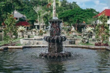 Photograph of an old Bali fountain of stone standing in the waterの写真素材