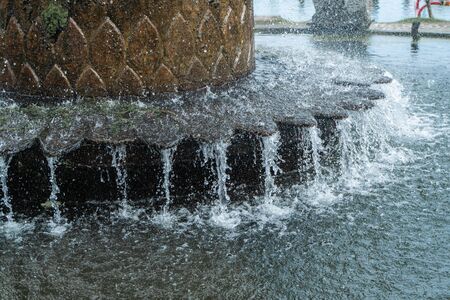 Photograph of an old Bali fountain of stone standing in the waterの写真素材