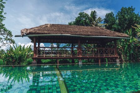 Photo of a tropical summer backyard with a large gazebo, pool and palm trees in the backgroundの写真素材