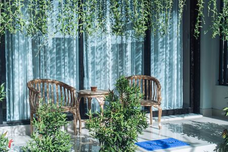 Photo of a summer backyard with wooden chairs and a table, green grass and bushes