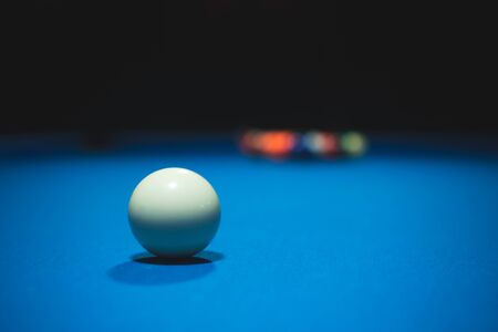 Photo of a blue pool table with a white ball down the middle in a dark roomの写真素材