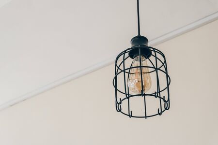 Photograph of black lamp molding mesh weighing on white ceiling on wireの写真素材