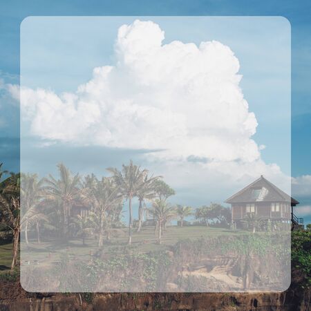 Photo of a high mountain with houses in the middle of green grass on top and clouds in the...