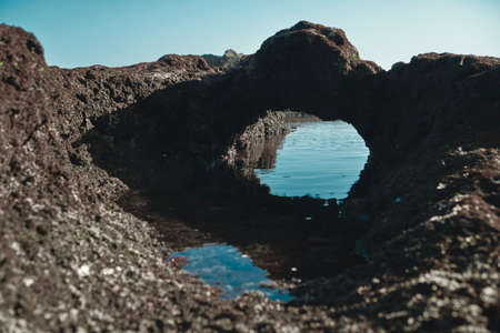 Photograph of an underwater marine colored ship with high cliffs in a sea tide of water with a reflection of the sky in the waterの写真素材
