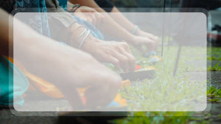 Photograph of the hands of people sitting in a lotus pose at an Indonesian ceremony handed over by...