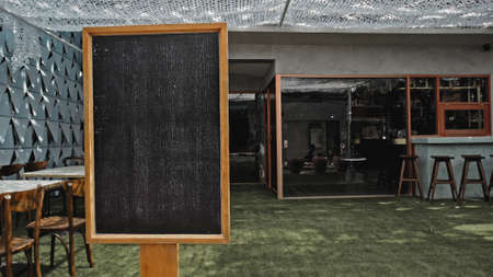 Black empty old chalk board standing indoors with green lawn