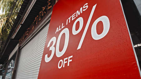 White text on a red banner standing on the street with the inscription 30% offの写真素材